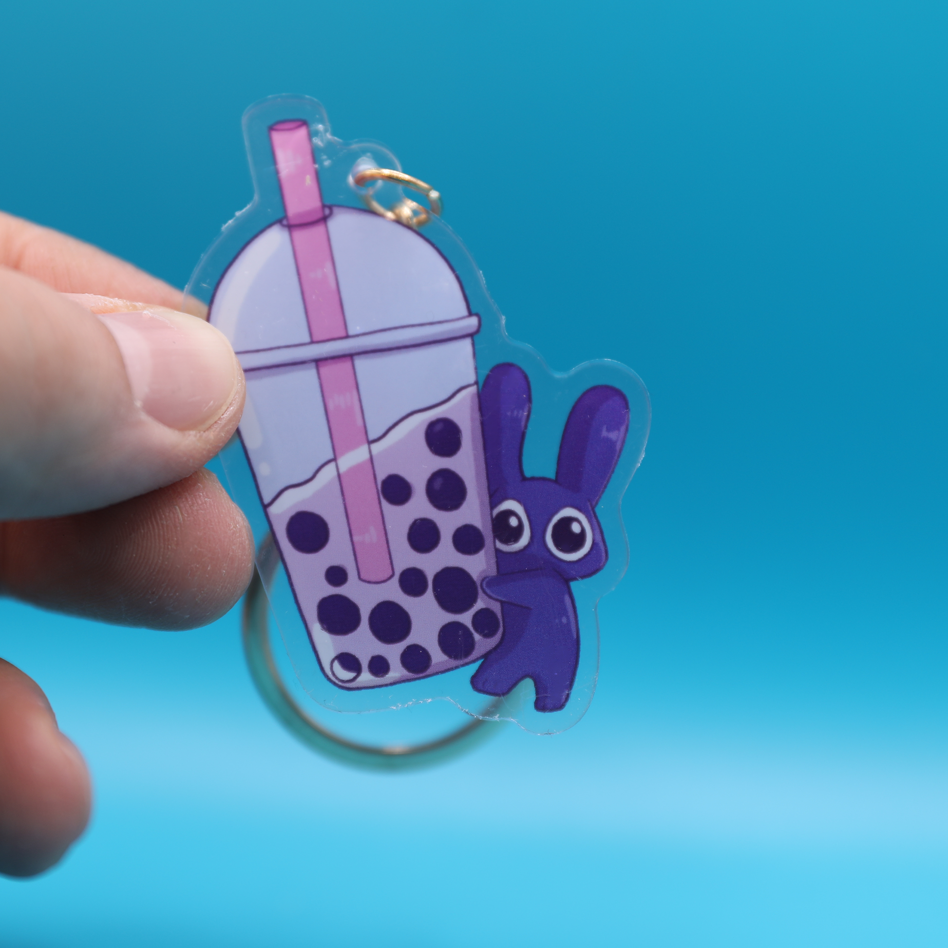 Keychain with a purple bunny character and bubble tea design on a blue background